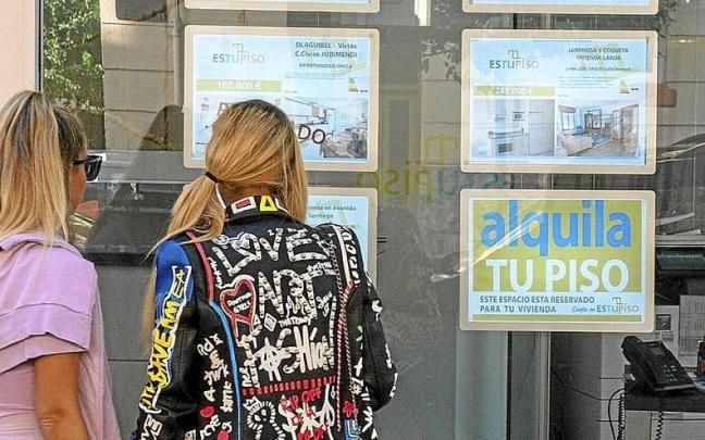 Lerro hauekin batera dagoen irudian, bi pertsonak Arabako etxebizitzen eskaintza ikusten. | ARGAZKIA: ALEX LARRETXI