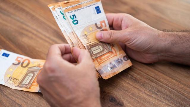 Un hombre cuenta billetes de 50 euros para pagar una deuda.