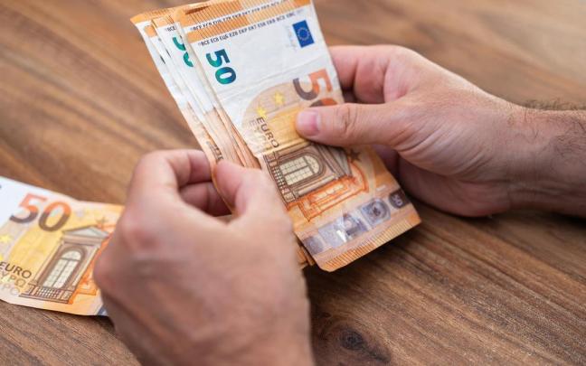 Un hombre cuenta billetes de 50 euros para pagar una deuda.