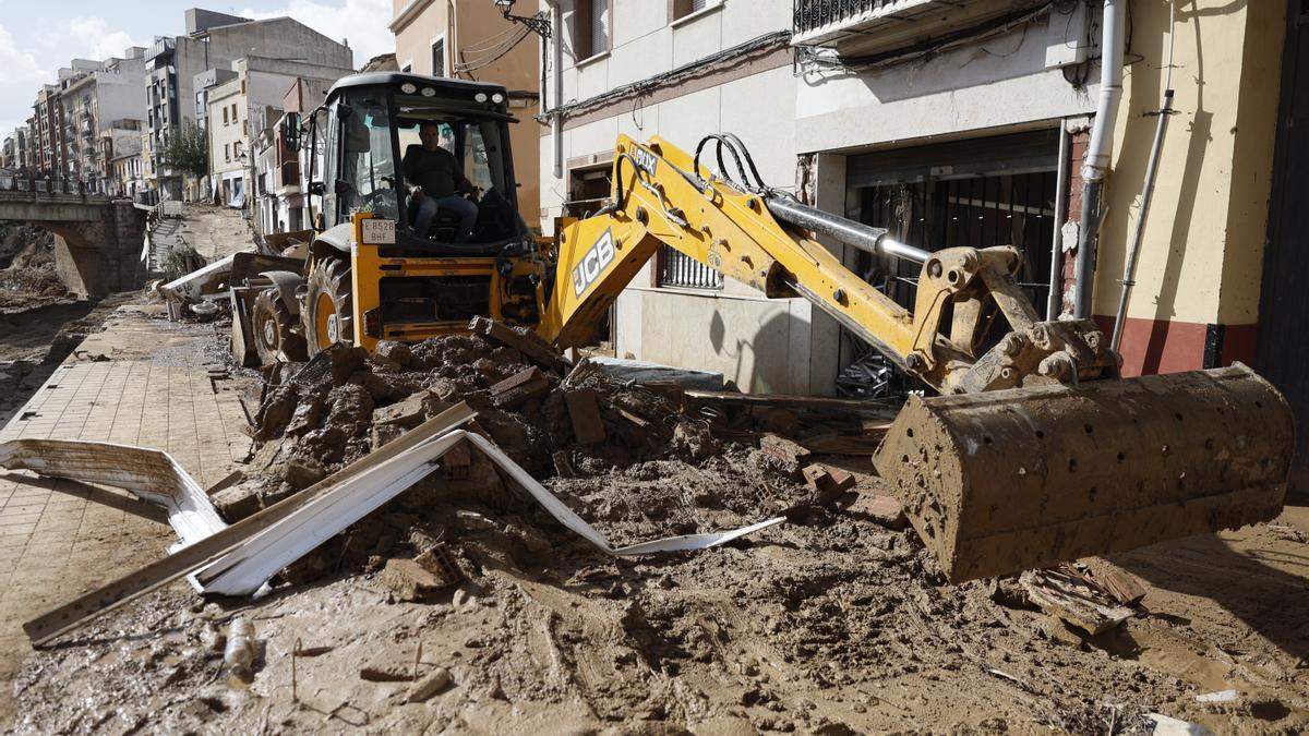 Una máquina escavadora retira el lodo acumulado en las calles de la localidad valenciana de Chiva.