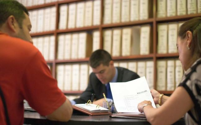 Personas ajenas a esta información repasando el contenido de un testamento en una Notaría.