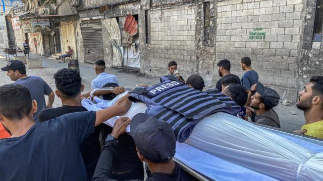 Un grupo de palestinos traslada el cuerpo de un periodista asesinado por Israel en Gaza.