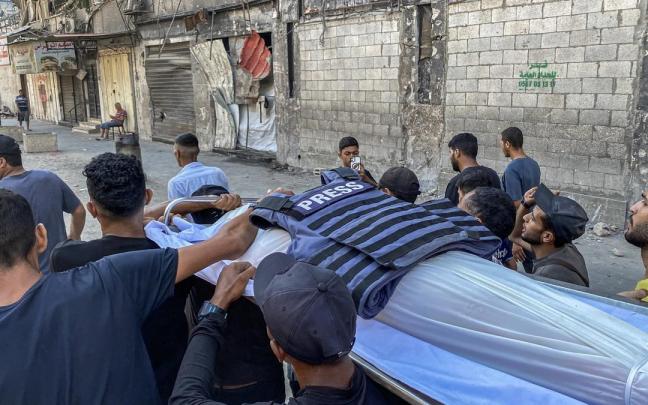 Un grupo de palestinos traslada el cuerpo de un periodista asesinado por Israel en Gaza.