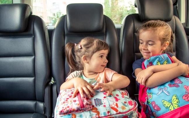 Niñas sentadas en el coche junto a sus mochilas.