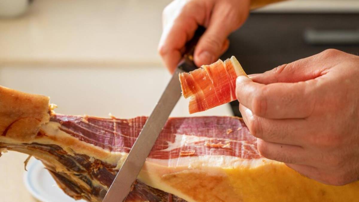 Primer plano de una persona cortando jamón