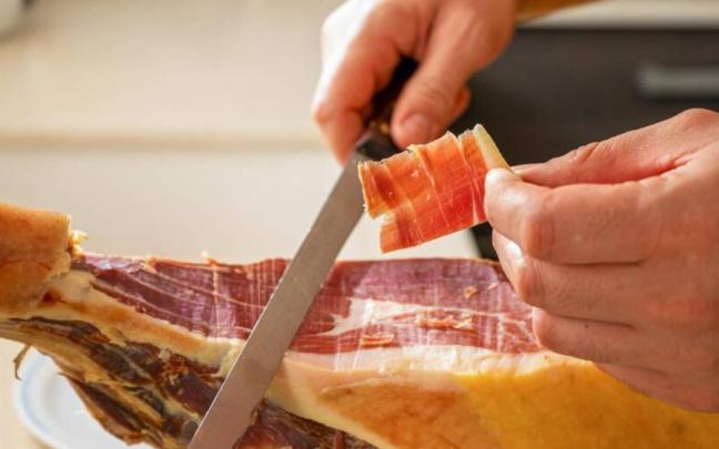 Primer plano de una persona cortando jamón