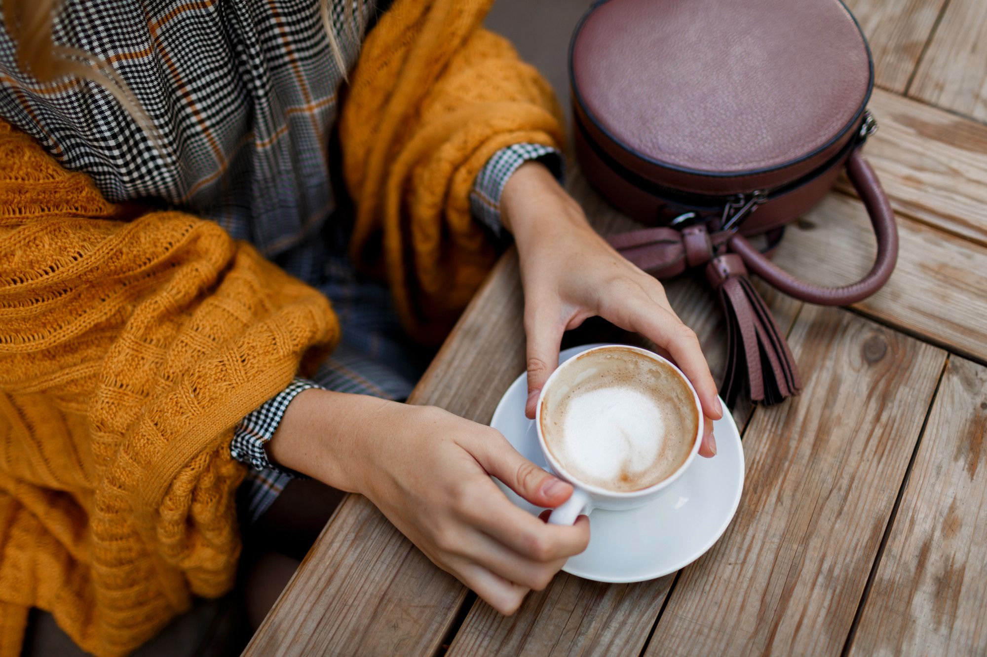 Una mujer toma una taza de café en una terraza.