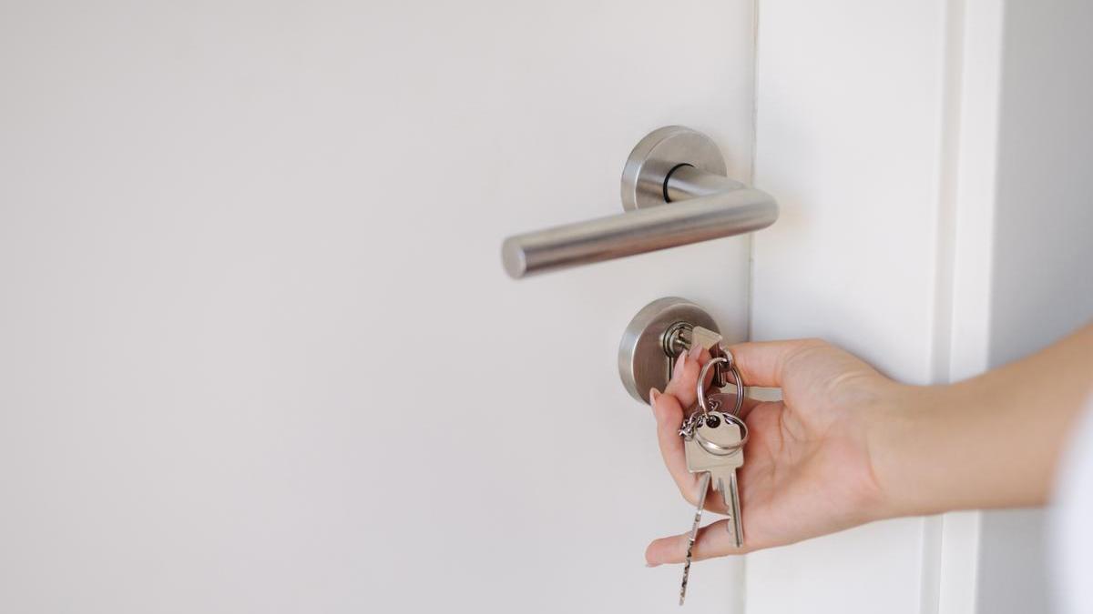 Manos de una mujer mientras cierra la puerta de la vivienda con llave.