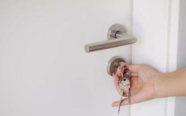 Manos de una mujer mientras cierra la puerta de la vivienda con llave.