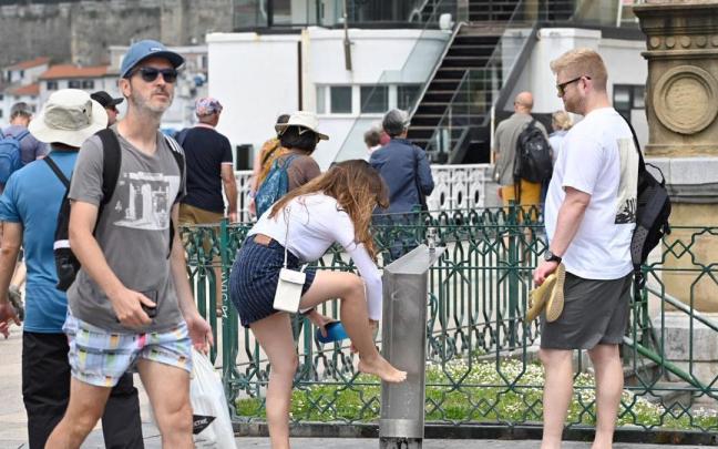 Una joven se refresca en una fuente en Donostia. / Arnaitz Rubio Una joven se refresca en una fuente en Donostia.