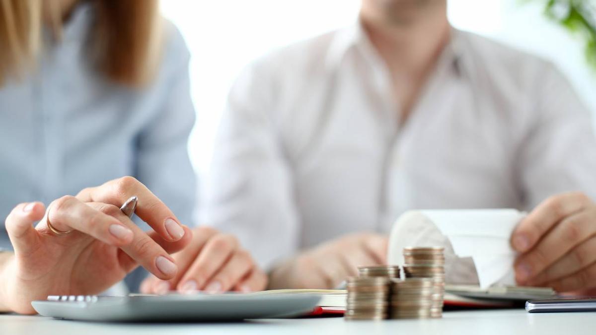 Dos personas realizan cálculos para conseguir un aval bancario