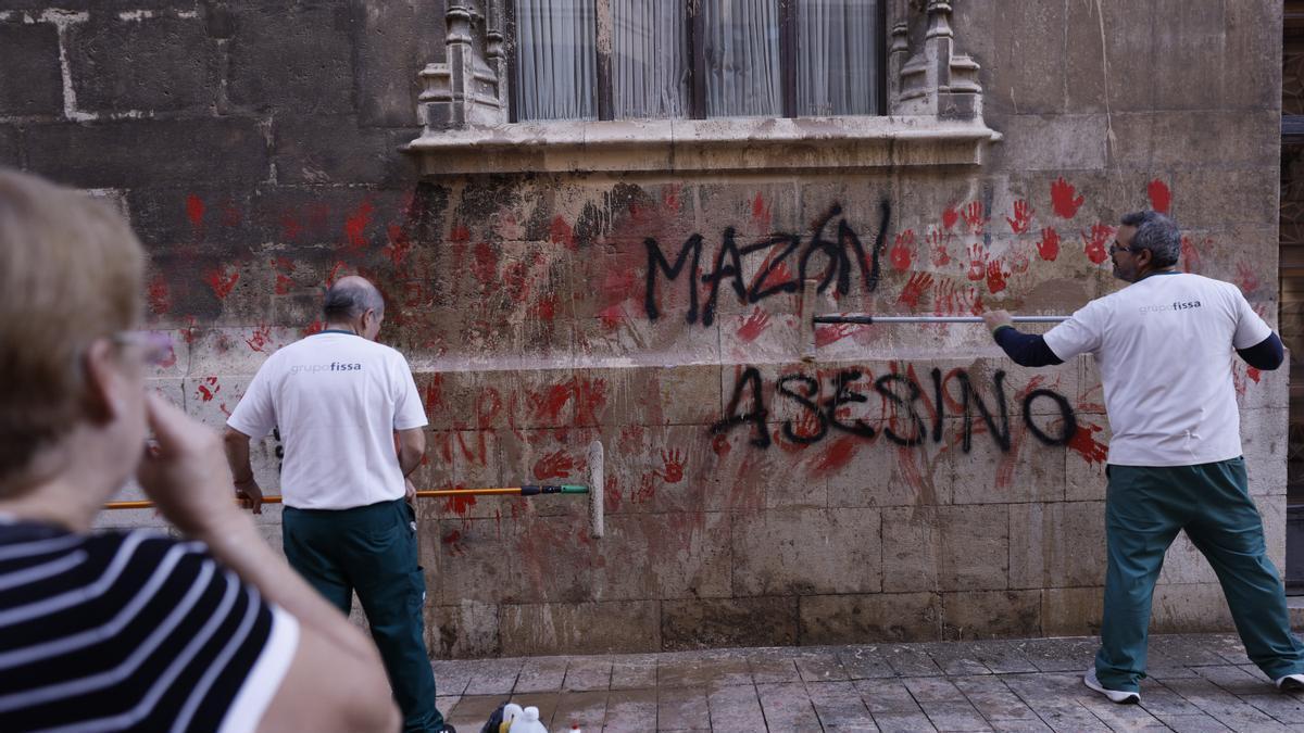 Los servicios de limpieza limpian las pintadas de la fachada de la sede del Gobierno valenciano tras la manifestcaión del sábado.