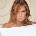 Una mujer con cara de enfado sujeta una almohada.