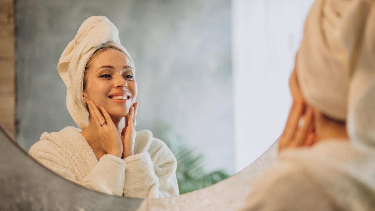 Reflejo en el espejo de una mujer con un cutis cuidado.