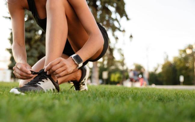 Una mujer se ata los cordones de las zapatillas antes de una sesión de entrenamiento
