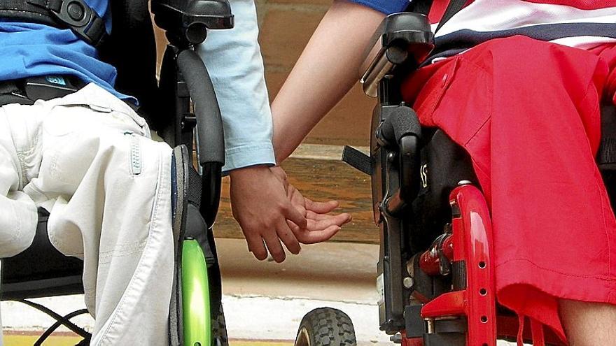 Personas en silla de ruedas dándose la mano en la sede de Aspace (asociación de parálisis cerebral de Álava).