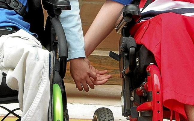 Personas en silla de ruedas dándose la mano en la sede de Aspace (asociación de parálisis cerebral de Álava).