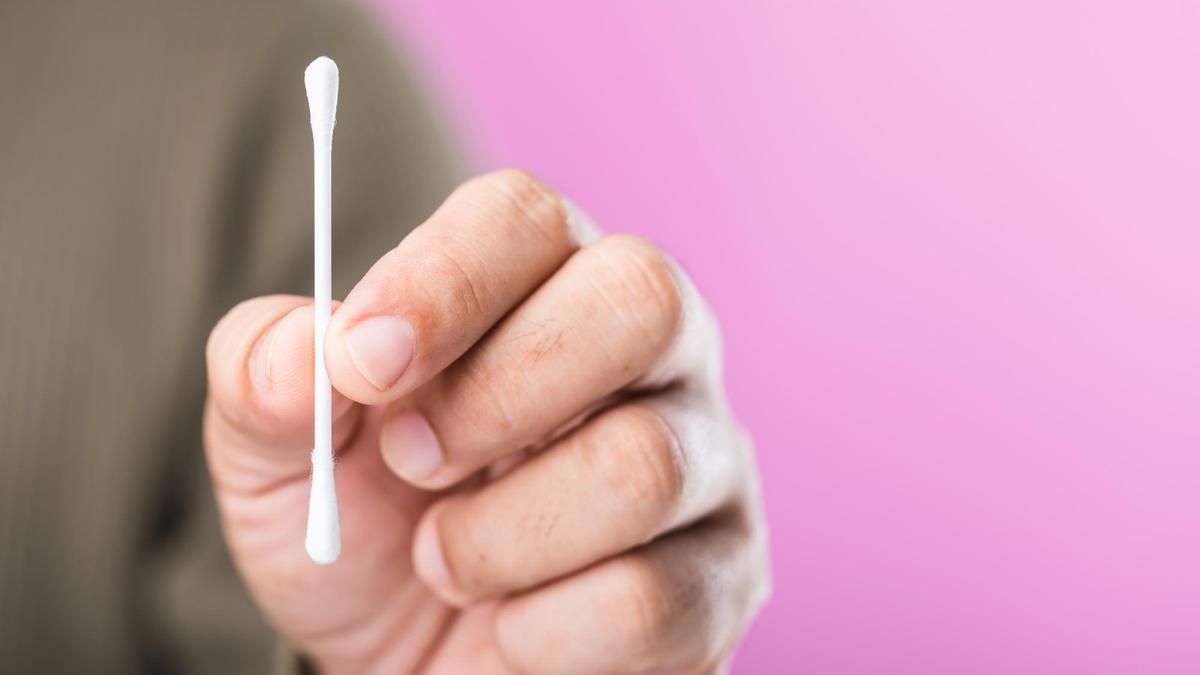 Un hombre sujeta con sus dedos un bastoncillo de algodón.