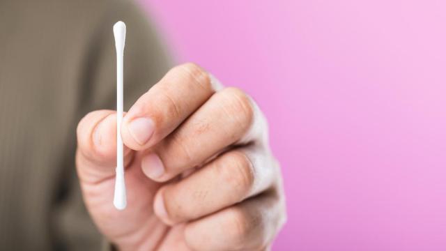 Un hombre sujeta con sus dedos un bastoncillo de algodón.