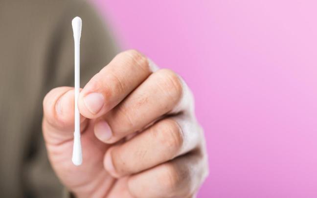 Un hombre sujeta con sus dedos un bastoncillo de algodón.