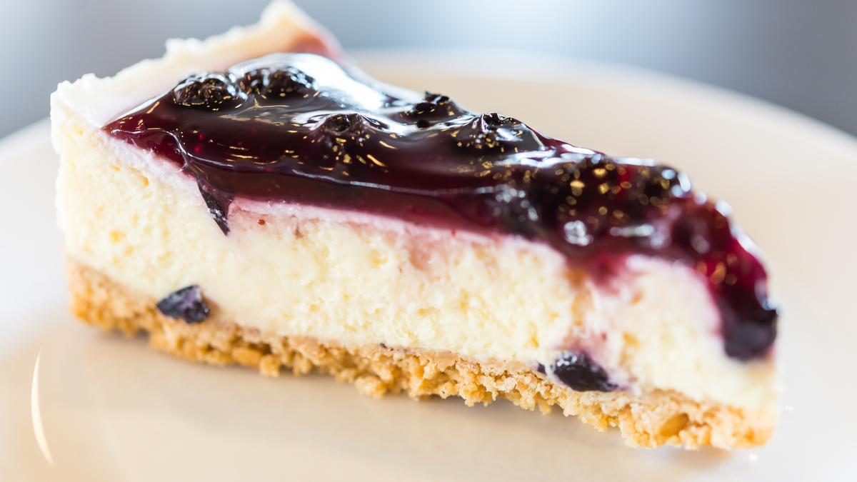 Una porción de tarta de queso con salsa de arándanos.