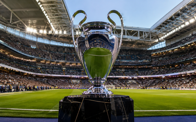 Trofeo de la Liga de Campeones sobre un pedestal en el campo de un estadio lleno