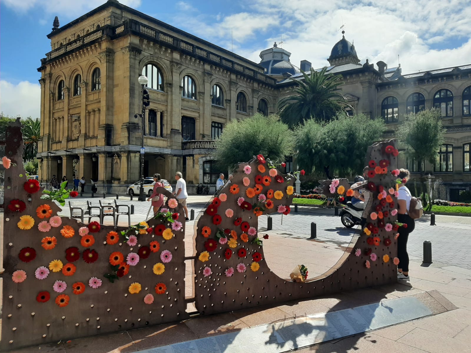 Escultura 'Dual' con las margaritas de colores depositadas durante la ofrenda floral