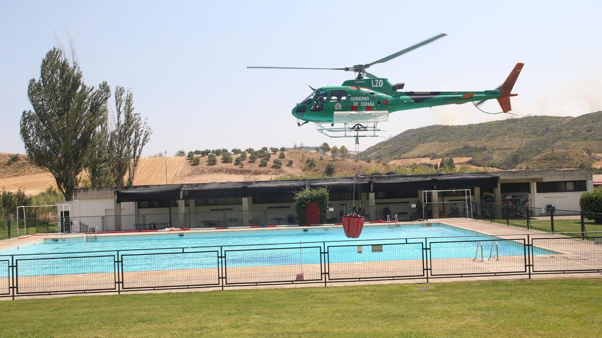 Un helicóptero, cogiendo agua de la piscina de Obanos para la extinción del incendio de Valdizarbe. Patxi Cascante