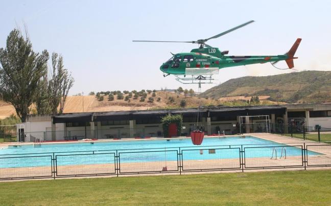 Un helicóptero, cogiendo agua de la piscina de Obanos para la extinción del incendio de Valdizarbe. Patxi Cascante