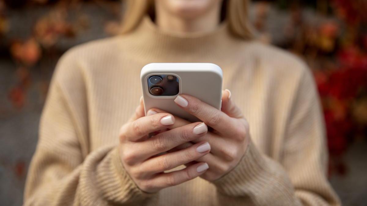 Una mujer sujeta un iPhone. FREEPIK