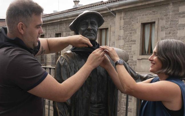 Iñaki Kerejazu y Nerea Martínez Aranburuzabala colocan el pañuelo de fiestas del 3M a la escultura de Celedón en la balconada de San Miguel. Alex Larretxi