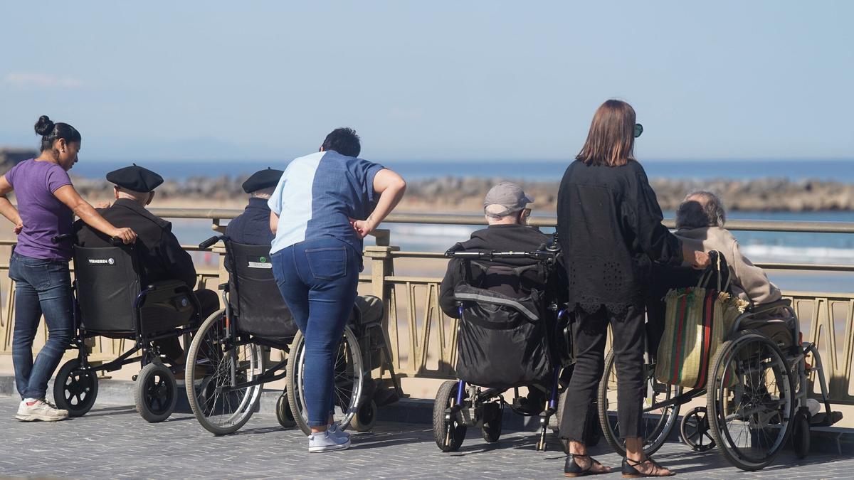Personas mayores en silla de ruedas acompañadas por cuidadoras, en la Zurriola. Ruben Plaza