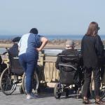Personas mayores en silla de ruedas acompañadas por cuidadoras, en la Zurriola. Ruben Plaza