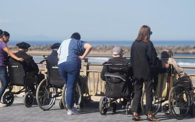 Personas mayores en silla de ruedas acompañadas por cuidadoras, en la Zurriola. Ruben Plaza