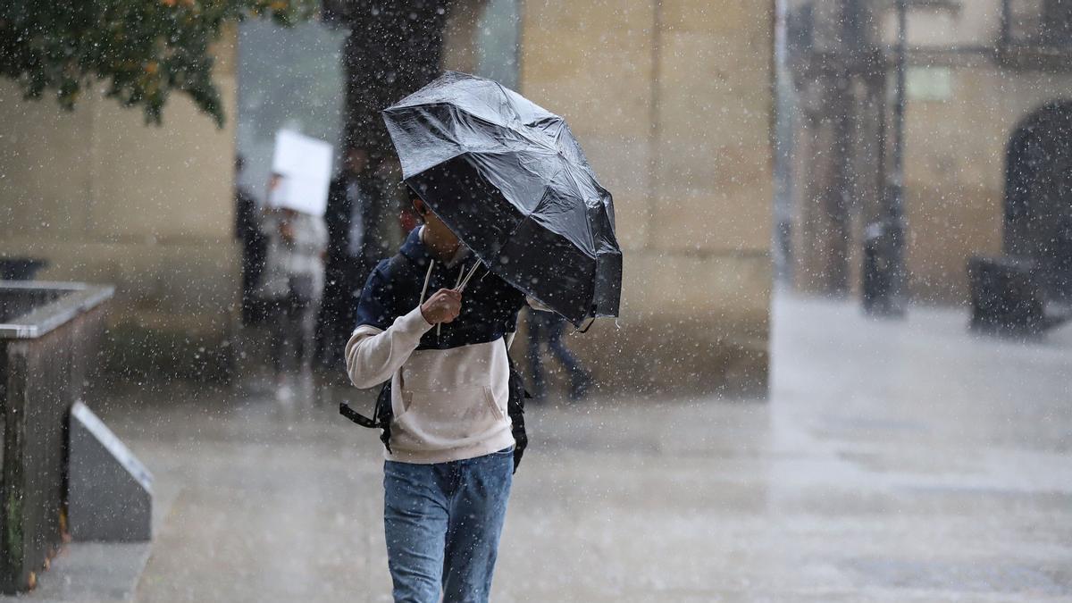 Un hombre intenta protegerse con el paraguas de la lluvia y el fuerte viento en una jornada lluviosa en Pamplona Javier Bergasa