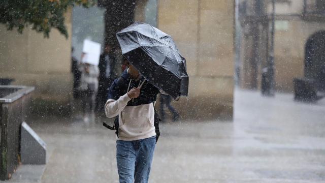 Un hombre intenta protegerse con el paraguas de la lluvia y el fuerte viento en una jornada lluviosa en Pamplona Javier Bergasa