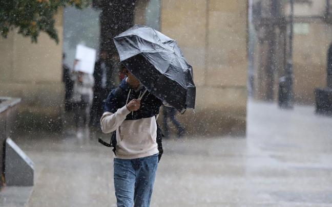 Un hombre intenta protegerse con el paraguas de la lluvia y el fuerte viento en una jornada lluviosa en Pamplona Javier Bergasa